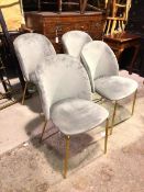 A set of four contemporary dining chairs, with upholstered backs and seats, on brass effect straight