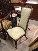 An early 20thc nursing chair, with foliate carved crest rail above an upholstered back and seat,
