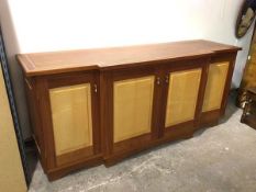 A modern breakfront sideboard, with inlaid top above four panel doors, with an arrangement of