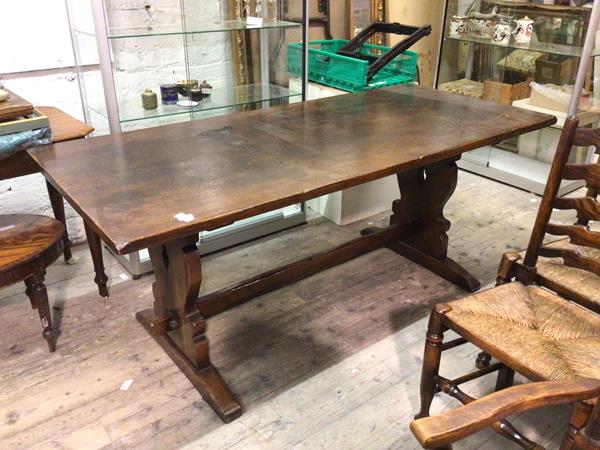 An oak trestle table, the rectangular top on pierced and moulded supports united by stretcher (
