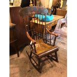 A Victorian ebonised rocking chair, the yoke style top rail with gilt foliate decoration above a