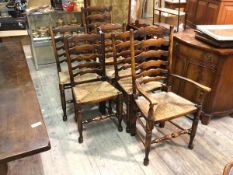 A set of six beech and elm dining chairs including two carvers, all with ladder backs, rush seats,