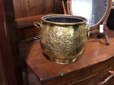 A brass jardiniere of bulbous form with lion mask handles to sides and heraldic crest to front (27cm
