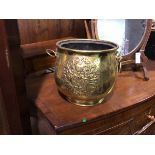 A brass jardiniere of bulbous form with lion mask handles to sides and heraldic crest to front (27cm