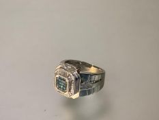 A gem-set cluster ring, the central square plaque pave-set with blue zircons, within a band of small