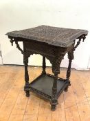 An Indian carved hardwood occasional table, the shaped square top profusely carved with figures,