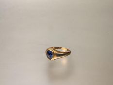 A single stone signet ring, the oval blue stone (possibly a sapphire) on a tapering yellow metal