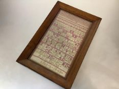A 19th century alphabet and numbers sampler, worked in red and green threads, signed "A.G.C. Dalziel