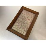 A 19th century alphabet and numbers sampler, worked in red and green threads, signed "A.G.C. Dalziel