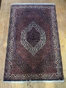 An Iranian hand knotted rugn the deep red, ivory and purple field with radiating lozenge design