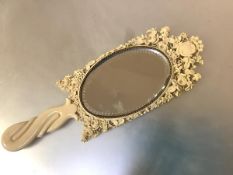 A Dieppe carved ivory hand mirror, 19th century, the oval plate within a frame elaborately carved