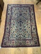 A hand-knotted ivory-ground rug of Persian design, the central field decorated with urns and foliage