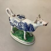 A 19th century Staffordshire cow creamer, the animal with Blue Willow transfer-printed decoration,