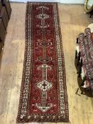 A Persian hand-knotted runner, the red ground with pole medallion, stylised bird and foliate