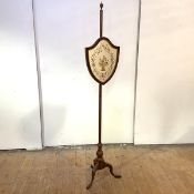 A George III mahogany firescreen, early 19th century, the rise and fall banner of shield form
