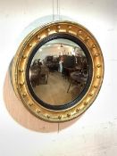 A Regency convex wall mirror, the cavetto moulded gilt frame applied with gilt spheres enclosing