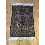 A silk-ground rug of Persian design, with all-over floral design centred by a concentric