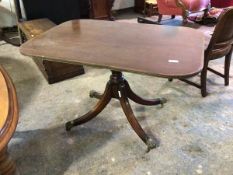 A Georgian style tilt top table with crossbanded edge on four footed support ending in brass paw