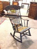 A Victorian ebonised rocking chair, the yoke style top rail with gilt foliate decoration above a