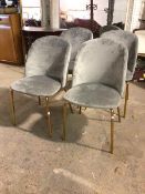 A set of four contemporary dining chairs with upholstered backs and seats, on brass effect