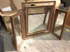 A triptych dressing table mirror, the hinged central mirror within a gilt and painted frame, flanked