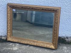 A gilt frame wall hanging mirror, the cushion and floral moulded frame with gilt slip having running
