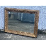 A gilt frame wall hanging mirror, the cushion and floral moulded frame with gilt slip having running