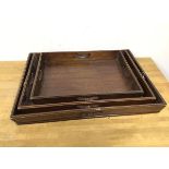 A set of three 1920s mahogany nesting trays, with raised moulded edges and pierced handles to four