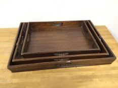 A set of three 1920s mahogany nesting trays, with raised moulded edges and pierced handles to four