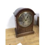 An Edwardian mantel clock, with arched top above a circular metal dial, with arabic numerals, on bun