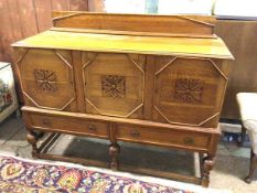 A 1930s/40s oak sideboard with ledge back above a rectangular moulded top over three panel doors