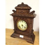 A 1920s mantel clock, the oak case with architectural carving, the dial with roman numerals (45cm