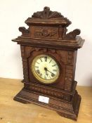 A 1920s mantel clock, the oak case with architectural carving, the dial with roman numerals (45cm