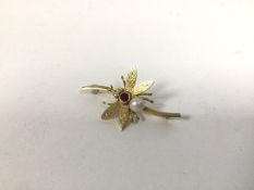 An 18ct gold bar brooch in the form of a winged insect, with two diamond chips to eyes, set red