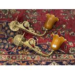 A pair of Edwardian cast brass wall sconces, each branch supporting a coloured glass shade with