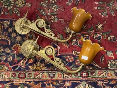 A pair of Edwardian cast brass wall sconces, each branch supporting a coloured glass shade with