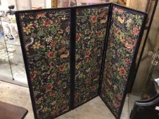 An ebonised three fold screen, the panels with flowers and deer, birds, dragon etc., panels to