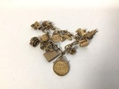 A charm bracelet, on yellow metal chain, markings rubbed, charms to include a 1913 half sovereign,