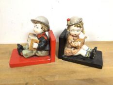 A pair of vintage bookends, each with a seated painted ceramic child playing an instrument (each: