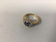 A 14ct gold dress ring with central blue stone surrounded by a ring of diamond chips and three to