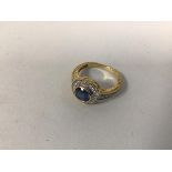 A 14ct gold dress ring with central blue stone surrounded by a ring of diamond chips and three to