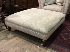 A large contemporary footstool upholstered in a patterned tufted silk fabric, raised on square