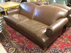 A modern sofa in chocolate brown leather upholstery, with scroll arms, two seat cushions, on