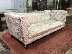 A large contemporary three seater sofa upholstered in a zebra pattern tufted fabric and raised on