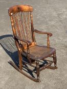 A 19thc mahogany open arm rocking chair, the shaped crest rail with sunburst inlay over a spindle