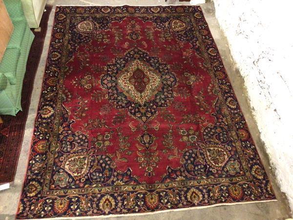 A Tabriz carpet with central foliate medallion, red field with indigo corners and border (380cm x