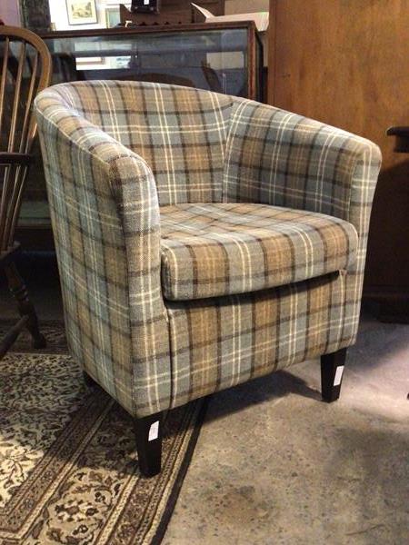 A contemporary tub shaped armchair upholstered in a tartan fabric with squab cushion, raised on