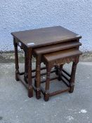 An oak nest of three tables, 20thc., each table having a square top over a lunette carved frieze,