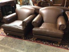 A pair of armchairs in chocolate brown leather with scroll arms, seat cushions, on tapering supports