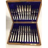 A set of twelve fruit knives and forks with mother of pearl handles and silver collars, the